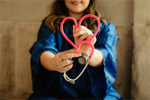 Bild zeigt eine weibliche Person die ein Stethoskop in Herzform in der Hand hält